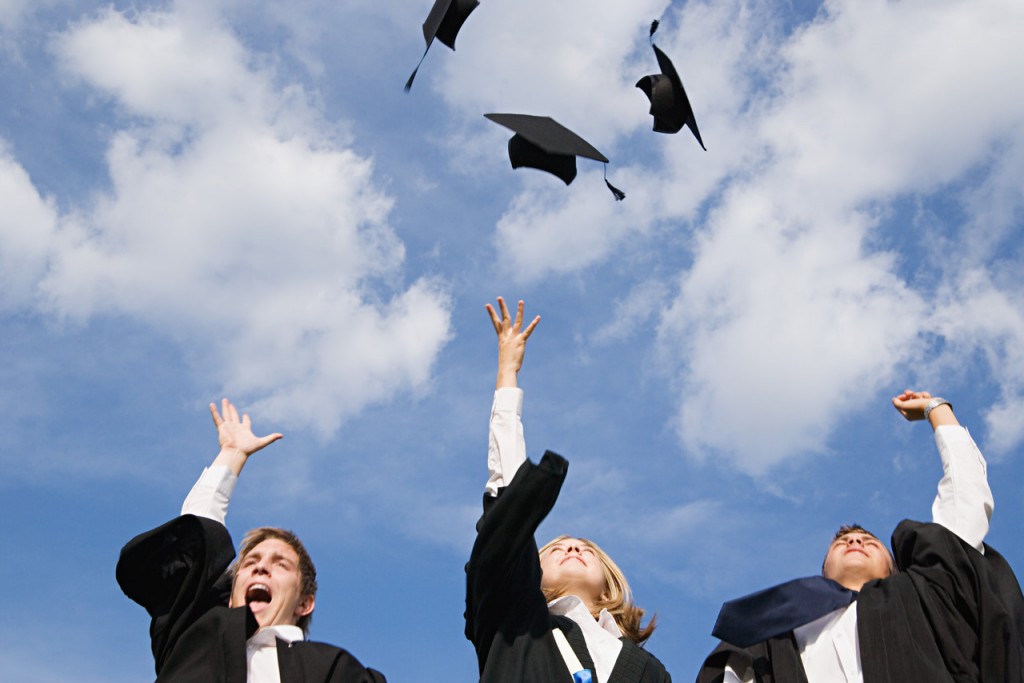 High school graduates throwing their mortarboards in the air